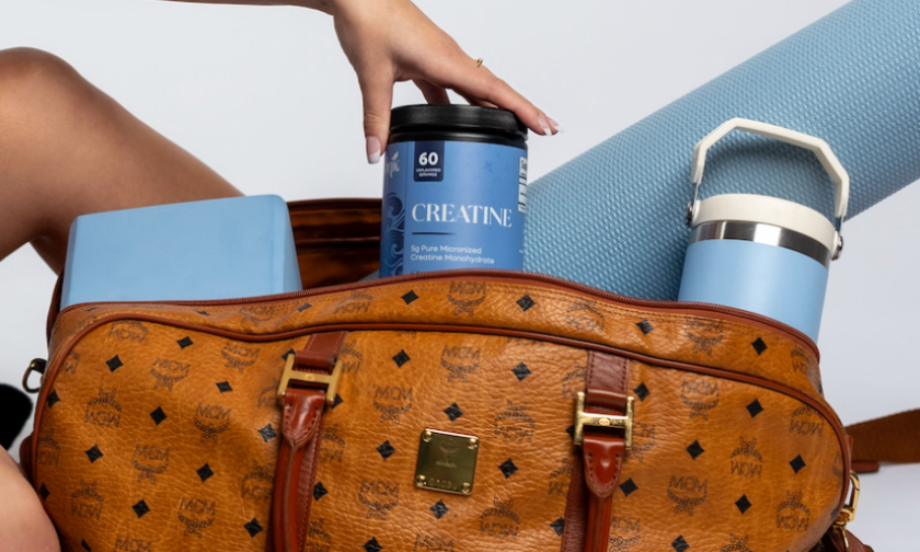 Woman sitting with a brown leather bag filled with books on a white background